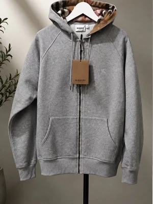 Grå hoodie från Burberry med dragkedja - Snygg grå zip hoodie från Burberry med klassiskt rutigt foder i huvan och dragkedja med Burberry-detalj. Tillverkad i mjukt bomullsmaterial och har ribbade muddar vid ärmslut och nederkant. Perfekt för en chill och stilren look. Storlek M och passar M. Priset kan diskuteras!