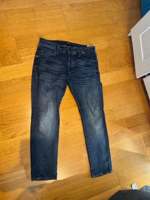 Marinblåa Jack&Jones jeans Slim/glenn W32 L30 - Snygga mörkblå slim fit jeans med klassisk femficksdesign och lätt slitna detaljer på framsidan. Jeansen har normal midja och raka ben, perfekta för en trendig och avslappnad look. Materialet är stretchigt för extra komfort. (Modell): jack & Jones (Slim/ Glenn) 