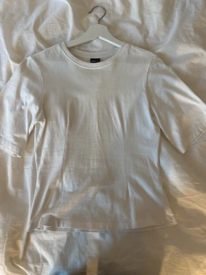 Vit Trekvarts ärmad T-shirt med insydda sömmar vid magen💛 - Har lite smink runt halsen som tyvärr inte går bort då det var där när jag köpte tröjan i butik💛