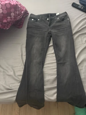 Grå bootcut jeans från True Religion - Säljer ett par gråa bootcut jeans från True Religion med snygga detaljer på bakfickan. Stolek W29. Använda 1 gång då dom var för små för mig som är 185cm 💕