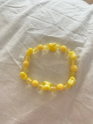 Gult pärlarmband med fjärilar - Ett sött armband med gula pärlor och fjärilar detaljer i plast. Armbandet är elastiskt och har en lekfull design som passar perfekt för att ge din stil en färgklick.egengjord