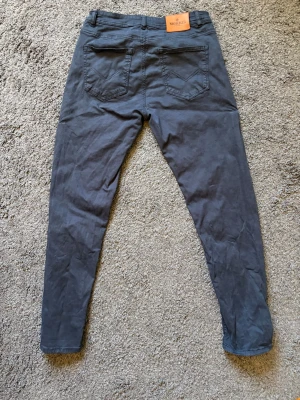Mörkblå jeans från Morris - Säljer ett par mörkblå jeans från Morris med halvsmal passform och klassisk femficksdesign. Jeansen har en snygg mörkblå färg och är tillverkade i mjukt bomullsmaterial. Perfekta för dig som gillar stilrena och bekväma jeans. Nypris 1599kr.