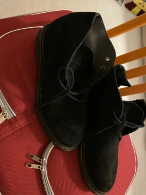 Svarta mocka stövletter med snörning - Säljer ett par svarta stövletter i mocka med snörning framtill. Skorna har en klassisk siluett och låg klack, perfekta för dig som gillar stilrena boots. Passar till många olika outfits och är riktigt snygga till jeans.