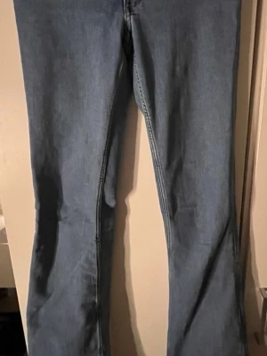 Blå bootcut jeans i klassisk modell - Snygga blå bootcut jeans med normal midja och klassisk femficksdesign. Jeansen har en lätt utsvängd passform nedtill och är tillverkade i ett mjukt denimtyg. Perfekta för dig som gillar en tidlös och avslappnad stil.