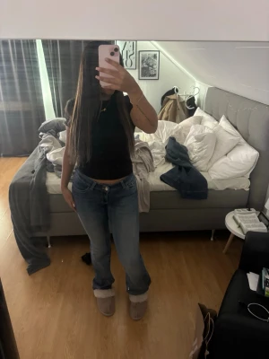 Blå raka jeans med låg midja - Säljer ett par blå jeans med låg midja och raka ben. Jeansen har klassisk femficksdesign och en lätt tvättad look med rosa detaljer både fram p bak. Perfekta för en avslappnad stil och passar till det mesta. Materialet är denim i bomull.