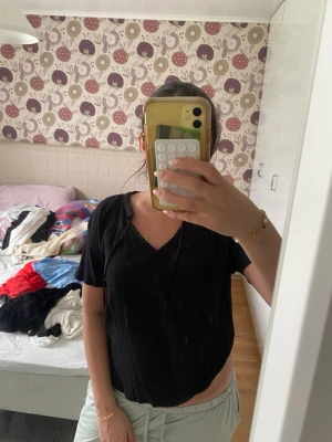 Svart v-ringad blus i bomull - Svart blus med v-ringning och korta ärmar. Toppen har en avslappnad passform och är tillverkad i ett lätt, krinklat bomullstyg som ger en skön känsla. Perfekt att styla med jeans eller kjol för en chill look.