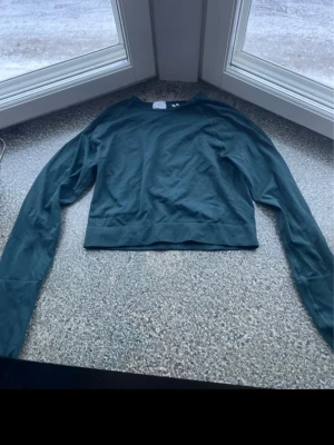 Träningströja  - En enkel och stilren mörkgrön/turkos croppad träningströja med långa ärmar och rund hals. Tillverkad i mjukt bomullsliknande material, perfekt för träning eller chill. 