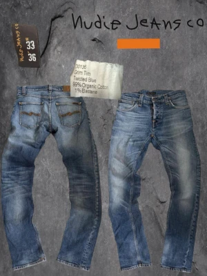 Nudie Jeans Grim Tim blå jeans - Säljer ett par Nudie Jeans Grim Tim i tvättad blå färg. Modellen har raka ben, klassiska fem fickor och kontrastsömmar. Tillverkade av 99% ekologisk bomull och 1% elastan för lite stretch. Snygg slitning och detaljer på bakfickorna.