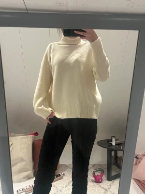 Krämvit stickad polotröja - Mysig krämvit stickad polotröja med avslappnad passform och breda ribbade muddar vid ärmslut och nederkant. passar perfekt för kyliga dagar.