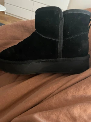 Svarta varmfodrade boots från Pace - Säljer ett par svarta boots från Pace med mjuk mockaliknande yta och varm, fluffig fodring på insidan. Skorna har en chunky sula och klassisk rundad tå. Perfekta för kalla dagar när du vill hålla stilen och värmen. Liknar uggs max använda 4 gånger