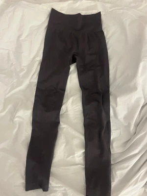 Svarta höga leggings utan märke - Säljer ett par svarta leggings med hög midja och tight passform. De är helt släta utan synliga loggor eller detaljer och har långa ben. Materialet känns stretchigt och mjukt.