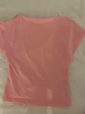 Ljusrosa topp med öppen rygg💞 - En enkel och snygg ljusrosa topp med öppen rygg och korta ärmar. Toppen har en lös passform och är tillverkad i mjukt bomullsmaterial, perfekt för en avslappnad look. Passar bra till både jeans och kjol. 💞