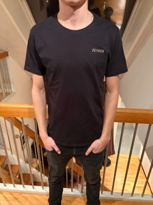 Svart t-shirt från Zenith - En stilren svart t-shirt från Zenith med diskret logga på bröstet. Klassisk rund halsringning och korta ärmar. Perfekt basplagg som funkar till allt och är lätt att matcha med andra kläder. Finns i storlek XS, S och M