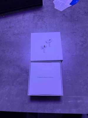 Apple AirPods Pro 2  - Säljer ett par Apple AirPods Pro med originalförpackning, extra silikonpluggar och USB-C laddkabel. Hörlurarna är vita och har en stilren, minimalistisk design i plast. Perfekta för dig som vill ha trådlösa in-ear hörlurar med grym ljudkvalitet och brusreducering.