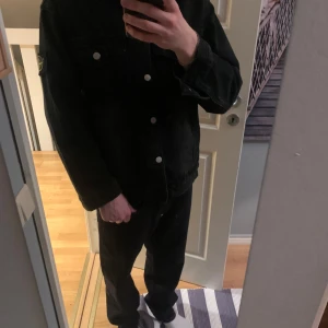 Svart jeansjacka - Säljer en svart jeansjacka från Stone Island med klassisk krage, knappstängning och två bröstfickor.