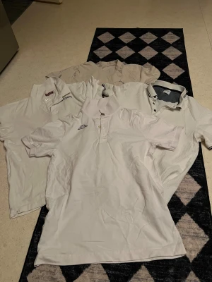 Beige och vita pikétröjor & t-shirt - Säljer ett paket med flera pikétröjor i vitt och beige från olika märken, samt en beige t-shirt med trycket 'VACATION MODE' på bröstet. Pikétröjorna har klassisk krage och knappar, medan t-shirten har rund hals och kort ärm. Perfekt för en clean och enkel stil. En för 35kr.   Allt för 130kr