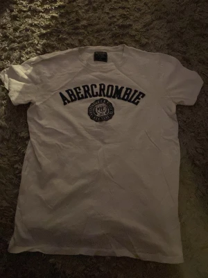 Vit Abercrombie t-shirt med tryck - Klassisk vit t-shirt från Abercrombie & fitch. Storlek S