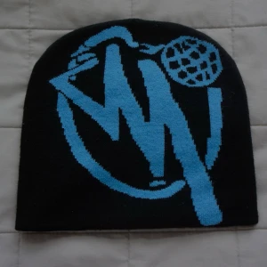 Minus- two | Mössa  - Cool svart mössa med stort blått grafiskt tryck framtill. Trycket har en street-art känsla med abstrakta former och detaljer. Mössan är mjuk och stretchig, perfekt för dig som vill sticka ut med din stil.