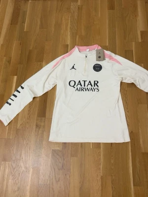 PSG x Jordan långärmad träningströja – beige/rosa - Paris Saint-Germain x Jordan collab med Qatar Airways-tryck framtill. Beige bas med rosa detaljer och svarta loggor. Perfekt för träning eller streetwear-look.  Fint skick. Riktigt clean färgkombination.