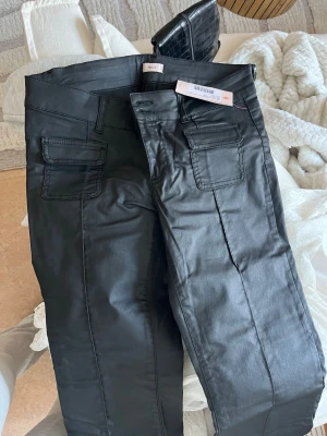 Helt nya Low Waist Bootcut Jeans från Nelly! ✨ - Säljer dessa supersnygga jeans i "coated" material som ger en cool skinn-look. De är helt nya och lappen sitter kvar! Säljer dem då de tyvärr inte passade mig. Modellen är låg i midjan med snygga fickor framtill och bootcut-ben – perfekt för både fest och vardag.                                                                •Märke: Nelly. • Modell: Low Waist Bootcut Pocket Jeans. • Storlek: EU 42  • Skick: Helt nya med tags. 