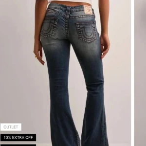 True Religion low waist bootcut jeans - Snygga blå jeans från True Religion med bootcut passform och klassisk röd kontrastsöm. Jeansen har ikoniska bakfickor med broderad logga och en patch med True Religion-märke bak i midjan. 