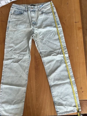 BOOHOOMAN Ljusblå raka jeans med hög midja - Säljer ett par BOOHOOMAN ljusblå jeans med rak passform och hög midja. Jeansen har klassiska fem fickor, bälteshällor och knappgylf. Materialet är denim i bomull och färgen är tvättad ljusblå. Perfekta för en avslappnad och trendig look.