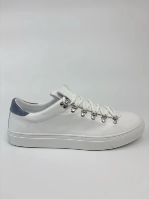 Vita Diemme sneakers med metallhål och mockadetalj - Stilrena vita sneakers med slät läderyta, robusta vita snören och silverfärgade metallhål för snörningen. Baktill finns en kontrasterande detalj i grå mocka. Snygg och minimalistisk design som passar till det mesta.