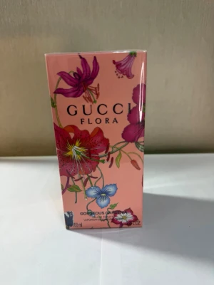 Gucci Flora Gorgeous Gardenia parfym - Gucci Flora Gorgeous Gardenia är en parfym i en snygg rosa kartong med blommigt mönster och detaljer i lila, rött och blått. Förpackningen är rektangulär och har en lyxig känsla. Märkt med både Gucci och Sephora.