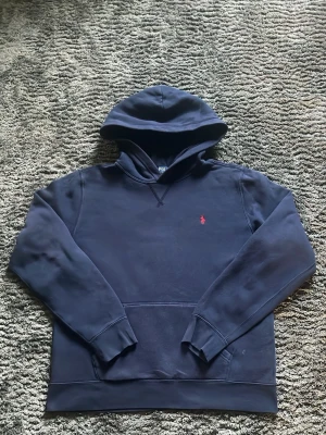 Blå Polo Ralph Lauren hoodie - Klassisk blå raffe hoodie med röd häst. Skick: 7/10. Storlek: XL (barn) Herr ca S-XS.