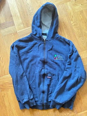 Mörkblå/ grå vintage hoodie från Dickies - Säljer en mörkblå /grå zip-hoodie från Dickies med broderad logga på bröstet och klassisk känguruficka. Hoodien har dragsko i huvan och mjukt innerfoder. Perfekt för dig som gillar streetwear och vill ha en bekväm och stilren look.