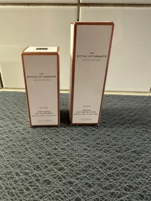 Ritual of Namaste Glow serum & ögonkräm - Säljer två produkter från Ritual of Namaste Glow-serien: ett anti-ageing serum och en anti-ageing ögonkräm. Båda innehåller saffransblomma och helig lotus. Förpackningarna är vita med roséguldsdetaljer och har en stilren, lyxig design.