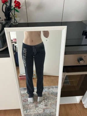 Mörkblå Hollister mjukisbyxor - Mörkblå mjukisbyxor från Hollister med vit logga längs ena benet. Byxorna har dragsko i midjan och raka ben. Tillverkade i mjukt bomullsmaterial som är skönt mot huden. Perfekta för en avslappnad stil. De har några fläckar (se blider) vet ej om de går bort 