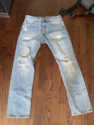 Levi's Premium ljusblå ripped jeans - Ljusblå jeans från Levi's Premium med raka ben och slitna detaljer på knäna och låren. Klassisk femficksmodell i denim med snyggt distressed look. Perfekta för en avslappnad och trendig stil.
