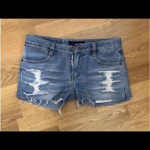 Blå slitna jeansshorts med fransar - Säljer ett par jättecoola blå jeansshorts med slitna detaljer och fransig nederkant.