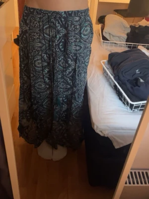 Mönstrad långkjol med snörning - Snygg långkjol med mörkblått och vitt mönster. Kjolen har en avslappnad passform och snörning i midjan med tofsar. Perfekt för sommardagar. Mönster som ingen annan kommer ha på sin kjol!