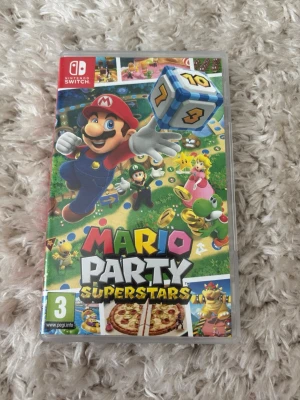 Mario Party Superstars till Switch - Mario Party Superstars till Nintendo Switch. Färgglad spelkassett och fodral med klassiska Mario-karaktärer som Mario, Luigi, Peach, Yoshi och Bowser. Perfekt för multiplayer och partykvällar. Spelet är i fysisk version med originalförpackning.