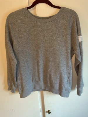 Grå sweatshirt från Björn Borg - Klassisk grå sweatshirt från Björn Borg med rund halsringning och ribbade muddar. Tröjan har en diskret logotyp på ärmen och är tillverkad i mjukt bomullsmaterial. Perfekt för en avslappnad och sportig stil.
