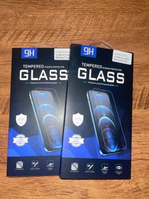 Skärmskydd i härdat glas iPhone 12 Pro - Säljer två paket skärmskydd i härdat glas för iPhone 12 Pro. Skydden är transparenta och har blåsvart förpackning. De är explosionssäkra, reptåliga och fingeravtrycksavvisande. Enkel installation med medföljande ram. Perfekt för att hålla mobilen fräsch och skyddad.