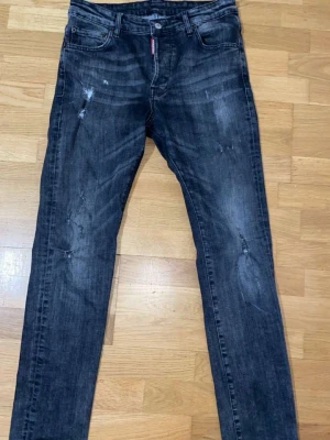 Grå Dsquared2 jeans - Snygga gråa jeans med slitningar och tvättad look. Jeansen har klassisk femficksdesign och smal passform. Perfekta för en cool och avslappnad stil.