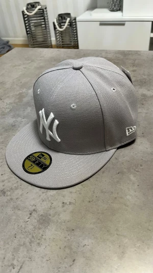Grå New Era NY keps 59FIFTY - Snygg grå keps från New Era med klassisk New York Yankees-logga broderad i vitt framtill. Modellen är 59FIFTY med rak skärm och broderade ventilationshål. Kepsen är tillverkad i ett slitstarkt tyg och har MLB-logga baktill.