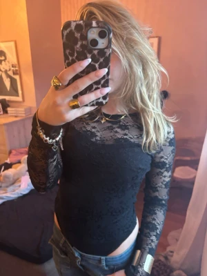 Svart spetsbody från Vero Moda - Säljer en svart långärmad spetsbody från Vero Moda. Toppen har ett genombrutet spetsmönster och sitter tight mot kroppen. Perfekt att styla med jeans eller kjol för en trendig look. Supersnygg strl S 