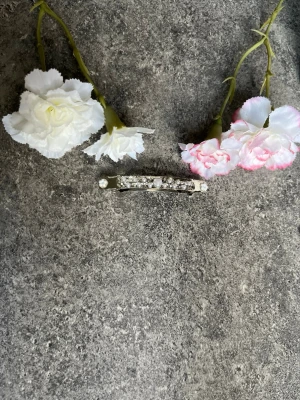 Handgjort hårspänne med pärlor - Snyggt hårspänne i silverfärg dekorerat med små vita pärlor och gnistrande stenar. Perfekt för att piffa till frisyren och ge en elegant touch 🤗🤍dessa designer på hårspännena är handgjorda och har lackats för att behålla sin skönhet