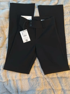 Svarta bootcut kostymbyxor bershka  - Säljer ett par svarta kostymbyxor från bershka i modellen bootcut med två knappar. Helt oanvända! Storlek: 34 längd: short. (Kan byta till en större storlek i 38 eller 40 i längd: short) 