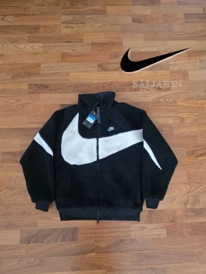 Nike Reversibel Fleece - 🖤🖤 Nike Reversibel Fleece – Storlek S 🖤 Exklusiv Nike-jacka i storlek M med två stilar i ett: svart sherpa-fleece med vit swoosh och Dri-FIT-teknologi, eller svart glansigt, vindtätt tyg med vit Nike-logga. Hög krage, hel dragkedja, ribbade ärmslut och fåll för bättre passform. Perfekt för sport och vardag. Ny med taggar. ✨ Detaljer: S (liten i storlek), reversibel, mjuk fleece + vindtätt tyg, Dri-FIT, nyskick. 📦 Snabb leverans – kontakta vid frågor!