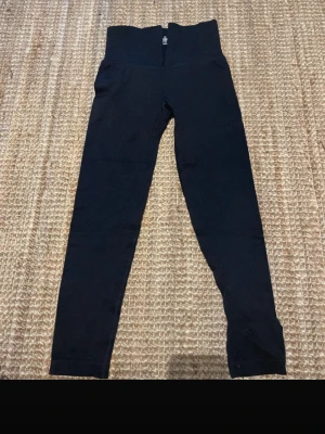 Svarta leggings med hög midja - Säljer ett par svarta leggings med hög midja och dragkedja fram. De är tillverkade i stretchigt material och har en tight passform som sitter snyggt på kroppen. Perfekta till både oversized tröjor och crop tops.