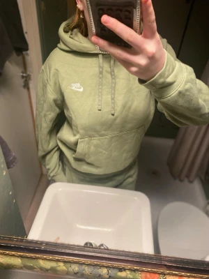 Ljusgrön hoodie från Nike byxorna och tröjan!! - Säljer en ljusgrön hoodie från Nike med klassisk logga i vitt på bröstet. Hoodien har magficka, dragsko i huvan och ribbade muddar vid ärmslut och nederkant. Tillverkad i mjukt bomullsmaterial som är riktigt skönt att ha på sig.