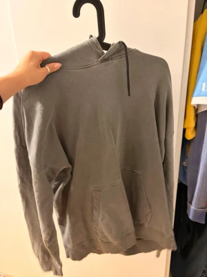 Grå hoodie från Only & Sons - Grå hoodie från Only & Sons med klassisk känguruficka och huva med snörning. Tillverkad i mjuk bomullsmix och har långa ärmar. Perfekt för en chill och avslappnad stil.