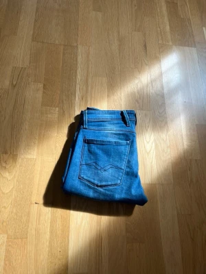 Blåa slim fit replay jeans - Snygga blåa slim fit replay jeans med klassisk femficksdesign och raka ben. Jeansen har en diskret logga på myntfickan och dekorativa sömmar på bakfickorna. Tillverkade i mjukt denimtyg som ger en bekväm passform.