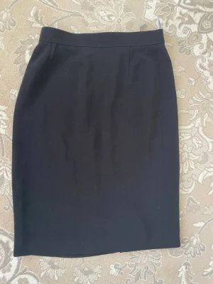 Gerry Weber  pennkjol med slits - Klassisk svart pennkjol i enkel och stilren design från Gerry weber ,kjolen  har en diskret slits bak och dragkedja i ryggen. Perfekt till både vardagsoutfits och mer uppklädda looks. Materialet känns mjukt och följsamt.