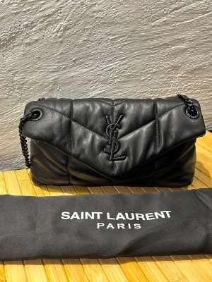 Svart YSL Puffer Bag - Säljer min Yves Saint Laurent Puffer bag i svart då den inte används längre. Den är köpt andrahand från StockX 2024 och har används snålt. Kommer från ett rök och djurfritt hem!